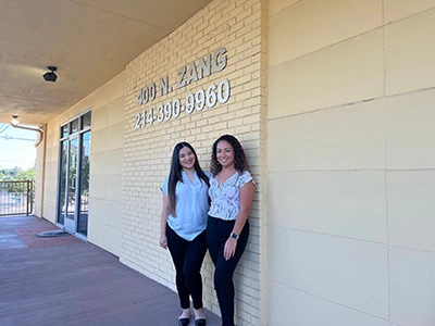 Dr. Trinh-Moore standing outside Bishop Arts Kids Pediatric Dentistry with her practice administrator Alejandra